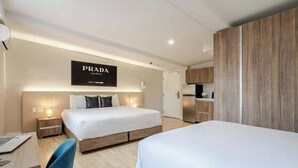 Una habitación de hotel moderna con una cama grande, un escritorio con una computadora portátil, un armario y un letrero en la pared.