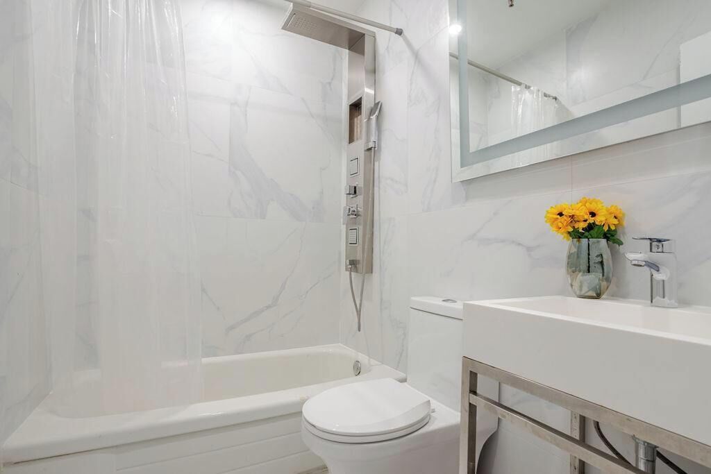 A bathroom with a bathtub, toilet, and a sink with a mirror above.