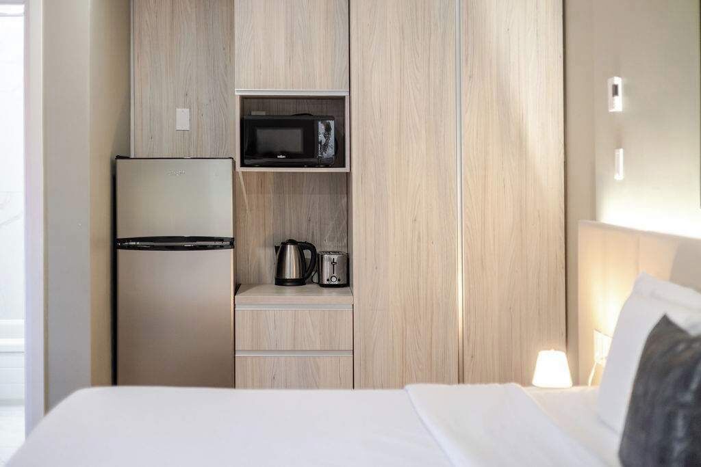 A hotel room with a bed, a minibar, a microwave, and a coffee maker.