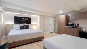 A modern hotel room with a large bed, a small desk, a kitchenette, and a sign for Prada Marfa. - Queen Duo – Heart of Montreal (Montréal)