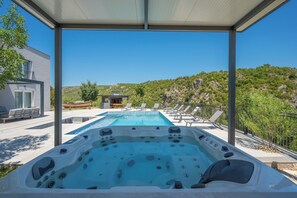 A hot tub with a view of a mountain and a pool area with lounge chairs. - Villa River Rose With Pool and Jacuzzi (Omis)