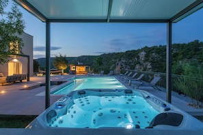 A hot tub with jets, surrounded by lounge chairs and a pool, set against a mountainous backdrop. - Villa River Rose With Pool and Jacuzzi (Omis)