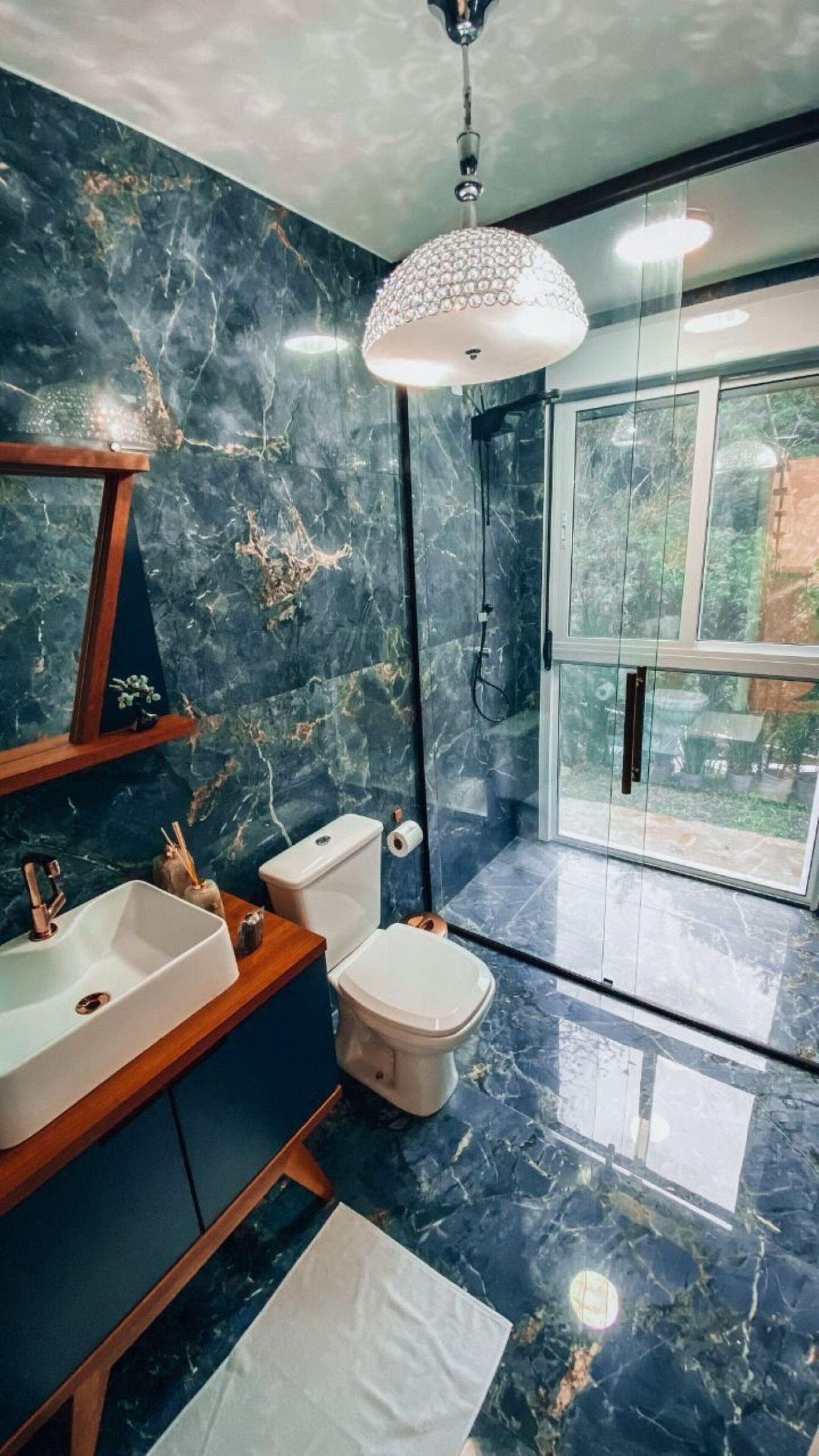 A bathroom with a marble floor, a sink, a toilet, and a shower.