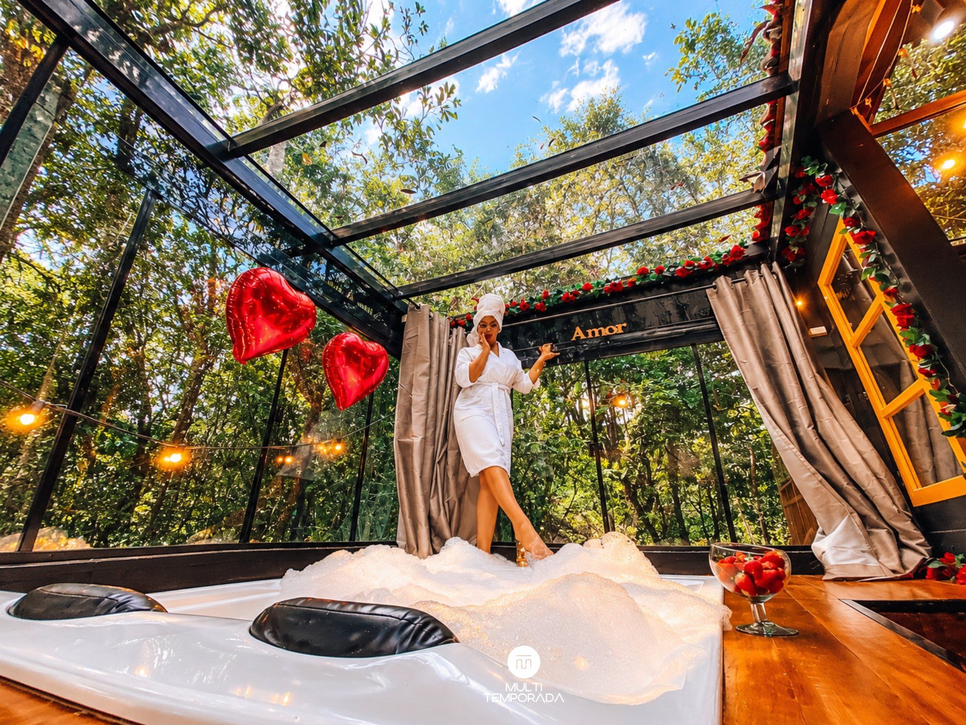 A room with a glass ceiling, a bed with a white cover, and a decorative heart-shaped balloon.