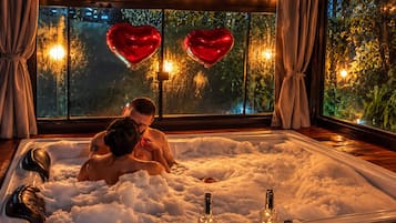 Una pareja en un jacuzzi con globos con forma de corazón y un letrero que dice 'para nos, todo amor do mundo'.