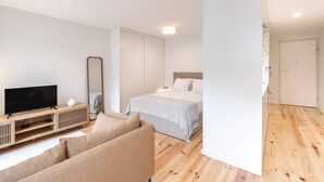 Et moderne soveværelse med seng, fjernsyn, sofa og spejl.