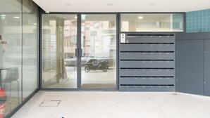 En moderne bygningseingang med en glasdør, en scooter parkeret udenfor og et keypad-adgangssystem.