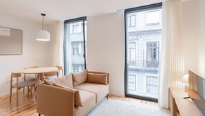 En moderne stue med sofa, spisebord med stole og et TV-bord.