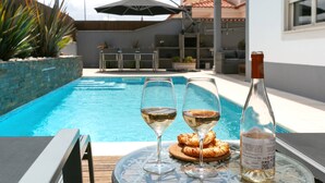 A poolside setting with two glasses of white wine, a bottle of wine, and a plate of pastries on a glass table. - Óbidos Pool & Charm - Pet Friendly (Óbidos)