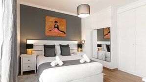 A modern bedroom with a large bed, bedside tables with lamps, a mirror, and artwork on the wall. - Óbidos Pool & Charm - Pet Friendly (Óbidos)