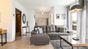 A modern living room with a sectional sofa, a glass coffee table, and a large window with curtains. - Óbidos Pool & Charm - Pet Friendly (Óbidos)