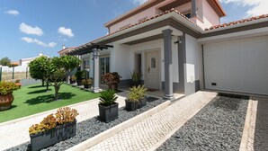 A modern house with a tiled roof, a covered porch, and a driveway leading to a garage. - Óbidos Pool & Charm - Pet Friendly (Óbidos)