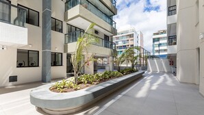 Un bâtiment moderne à étages, doté de grandes fenêtres et d’une cour intérieure agrémentée de plantes.