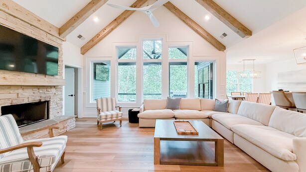 A spacious living room with a fireplace, a large sofa, a coffee table, and a television mounted on the wall. - Luxury Lake Home on Golf Course (Waleska)