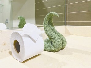 A bathroom with a toilet paper roll and a green towel on the counter.