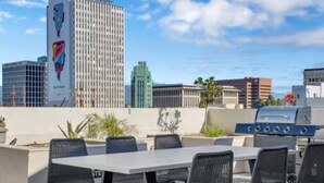 Une terrasse extérieure équipée d’un barbecue, de sièges et offrant une vue sur les bâtiments de la ville.