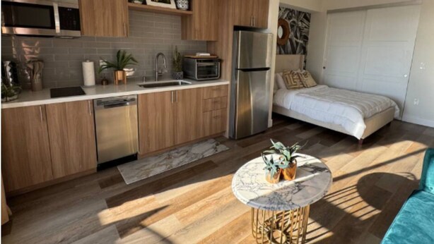 Une cuisine moderne avec des meubles en bois, des appareils en acier inoxydable et un plan de travail en marbre.
