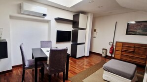 A modern living room with a dining area, a fireplace, and a mounted TV.