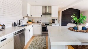 Une cuisine moderne avec des meubles blancs, un îlot central et une cuisinière intégrée.