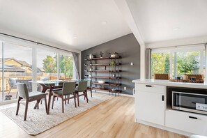 A modern kitchen with a dining area, large windows, and a built-in bookshelf. - Welcome to Cedars Edge. High end furnishings 3-bedroom house (Renton)