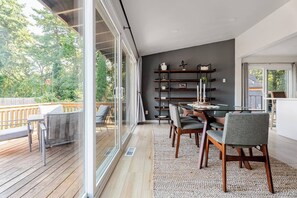 Een moderne eethoek met een glazen wand, een houten terras en een donkere accentmuur.