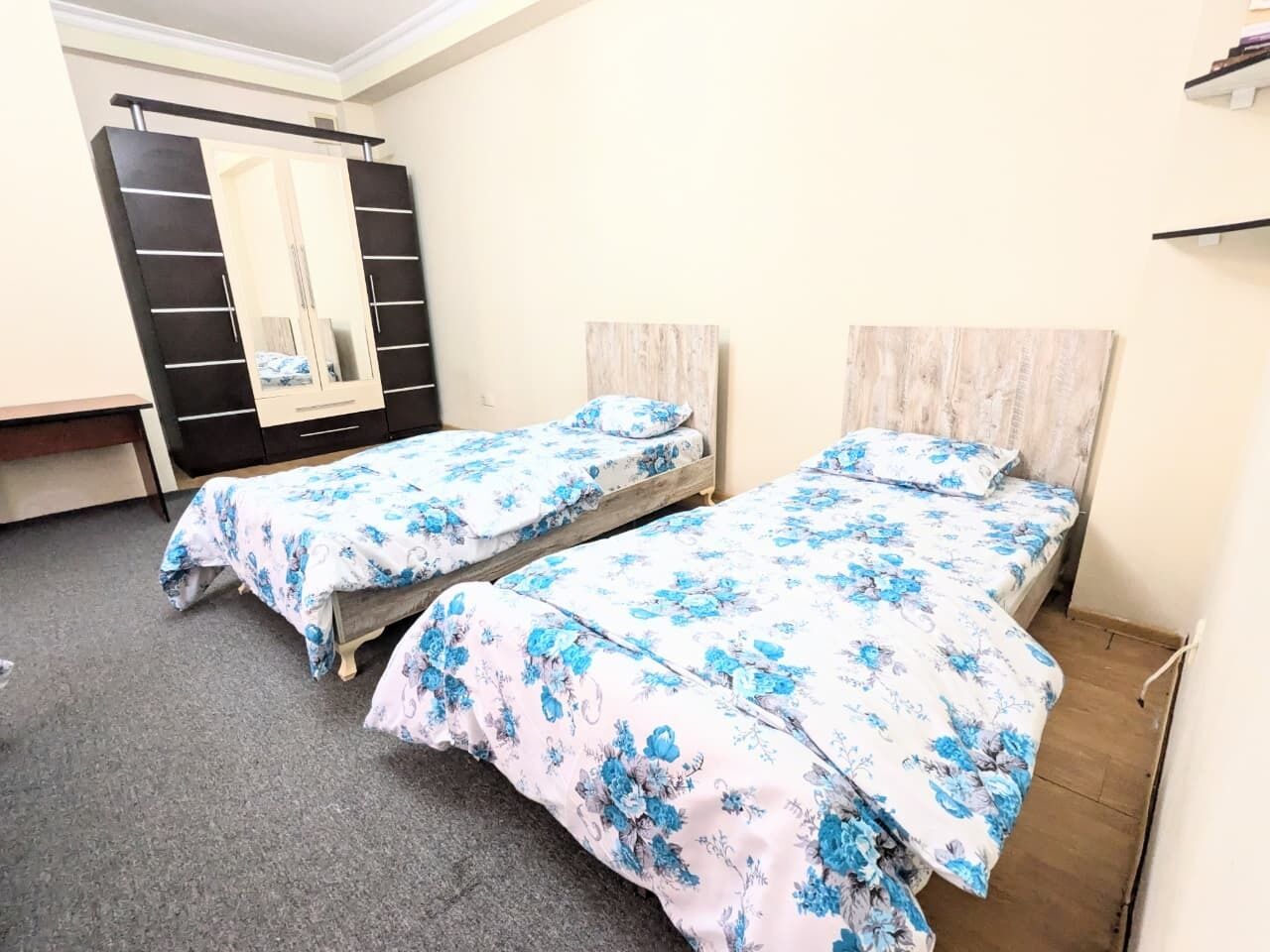 Une chambre avec deux lits simples, une armoire et un miroir.