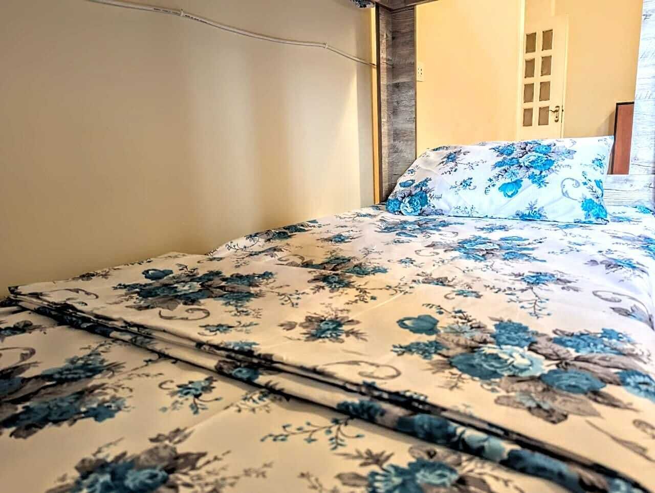 A bed with a floral bedspread and a matching pillow.