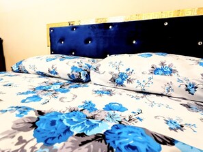 A bed with a floral bedspread and a tufted headboard. - Trippoo Villa & Hostel (Baku)