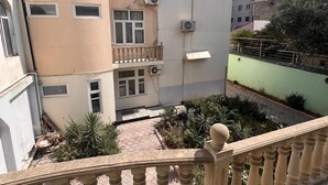 A multi-story building with a balcony, air conditioning units, and a paved courtyard. - Trippoo Villa & Hostel (Baku)