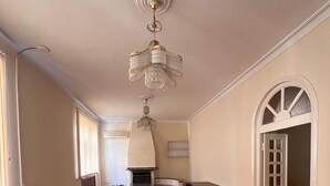 A spacious living room with hardwood flooring, a chandelier, a fireplace, and a dining area. - Trippoo Villa & Hostel (Baku)