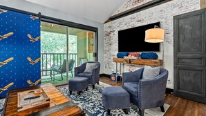 Un salón moderno con un televisor grande, asientos cómodos, una mesa de centro de madera y vistas al exterior.