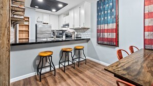 Una cocina moderna con gabinetes blancos, encimera negra y taburetes de madera.