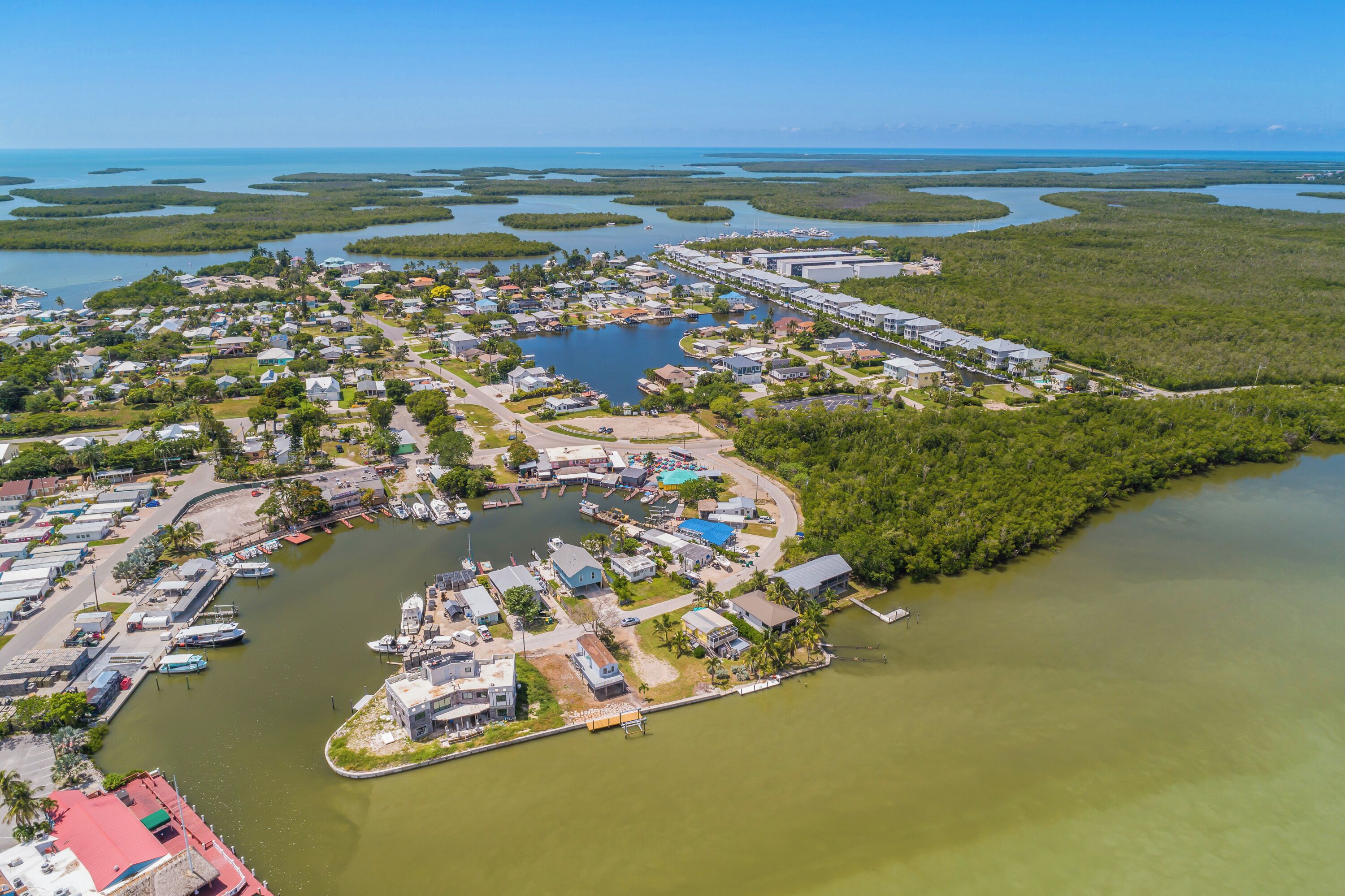An aerial view of a coastal town with a marina, residential areas, and a bridge connecting to the mainland.