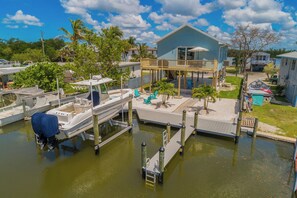 A marina with boats docked, a wooden dock, and a house with a balcony. - Harbor Place Boathouse, BRAND NEW DOCK, Open, on stilts, ocean front (Marco Island)