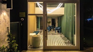 L'ingresso di un hotel con una porta in vetro, un vaso grande e un pavimento decorato.