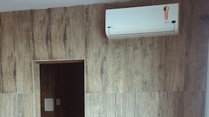 Una stanza con pannello in legno, un letto con copripiumino rosa e un condizionatore d'aria a muro.