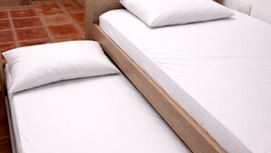 Una cama doble con ropa blanca y estructura de madera.