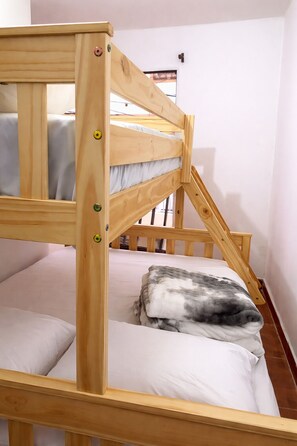 Un lit superposé avec une structure en bois et un matelas avec un oreiller.