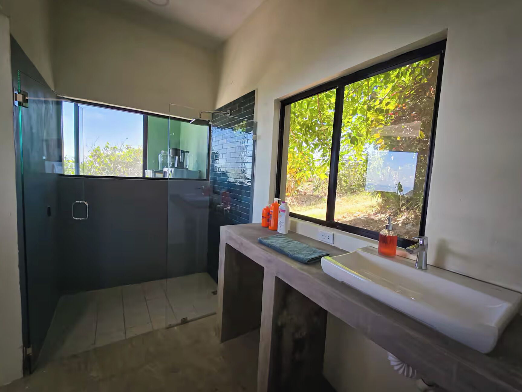 Une salle de bain moderne avec une grande fenêtre, un lavabo et un miroir.