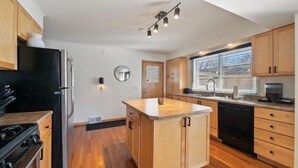 Een moderne keuken met houten kastjes, een zwarte koelkast en een centraal eiland.