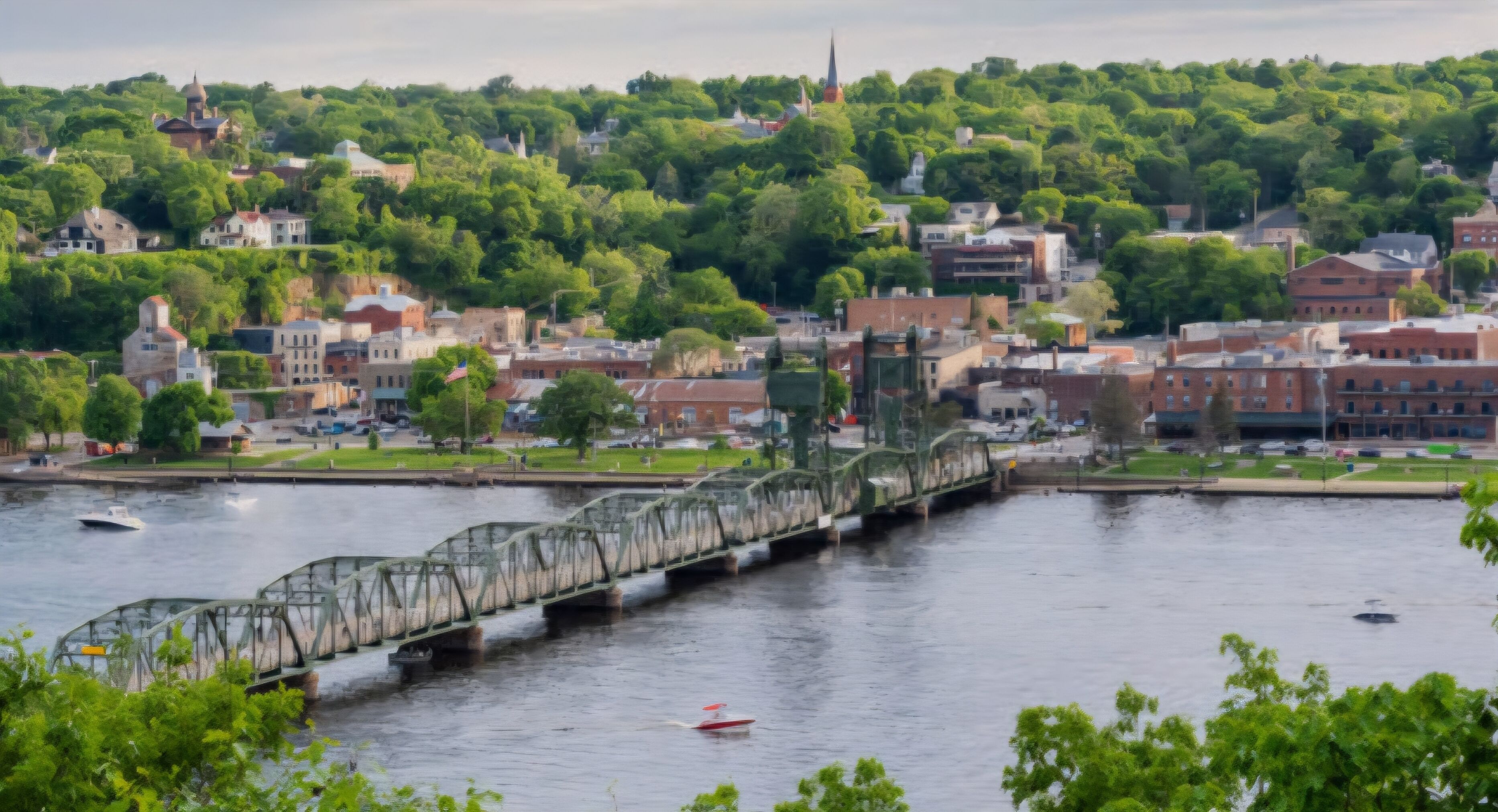 A river with a bridge, buildings, and greenery in the background.