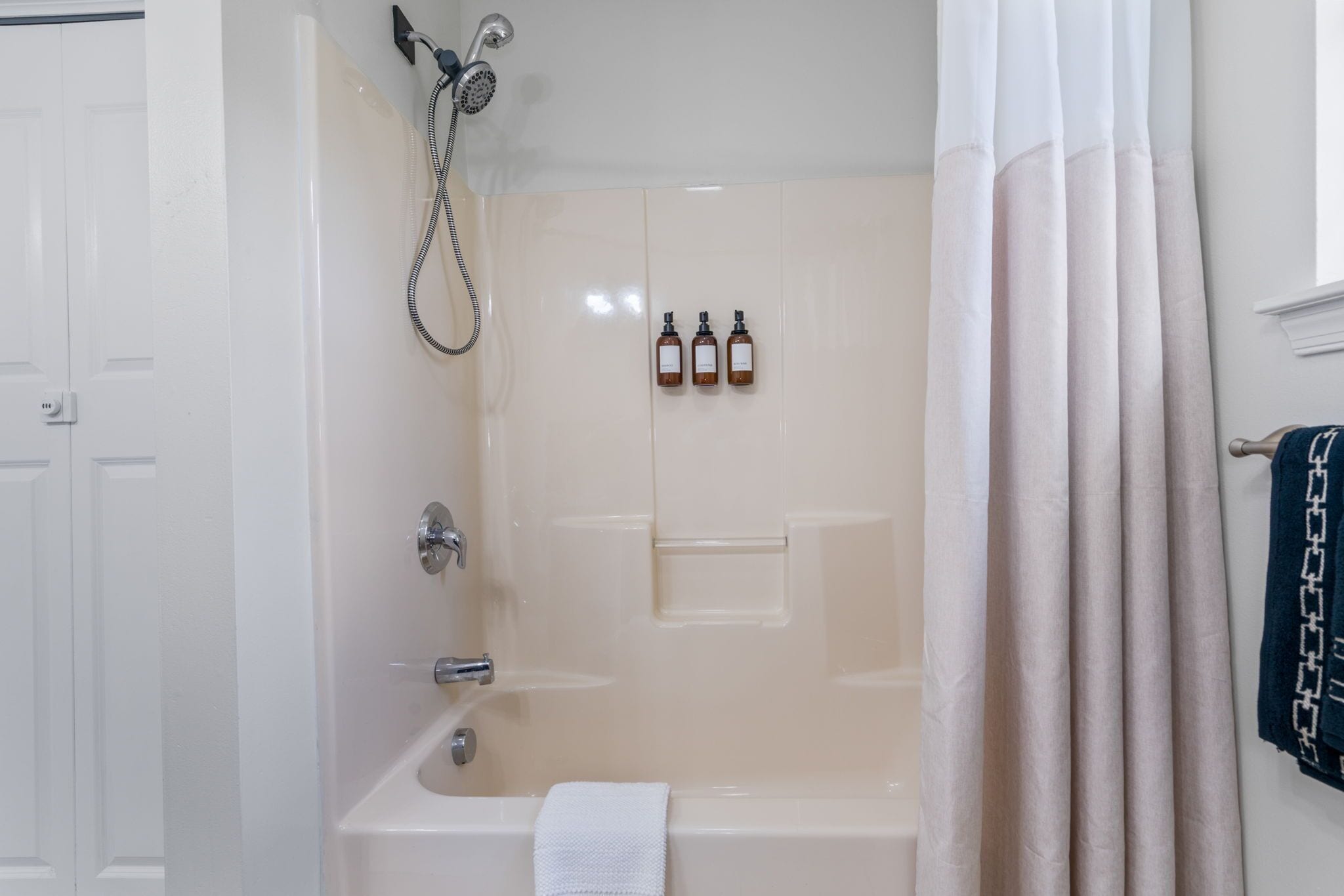 A bathroom with a bathtub, a shower, and three bottles of shampoo on the wall.