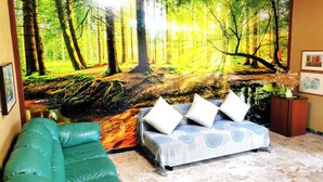 A living room with a green sofa, a patterned bed, and a forest-themed mural on the wall. - Large apartment near the lake and beach with mountain views in the greenery (Lombardia)