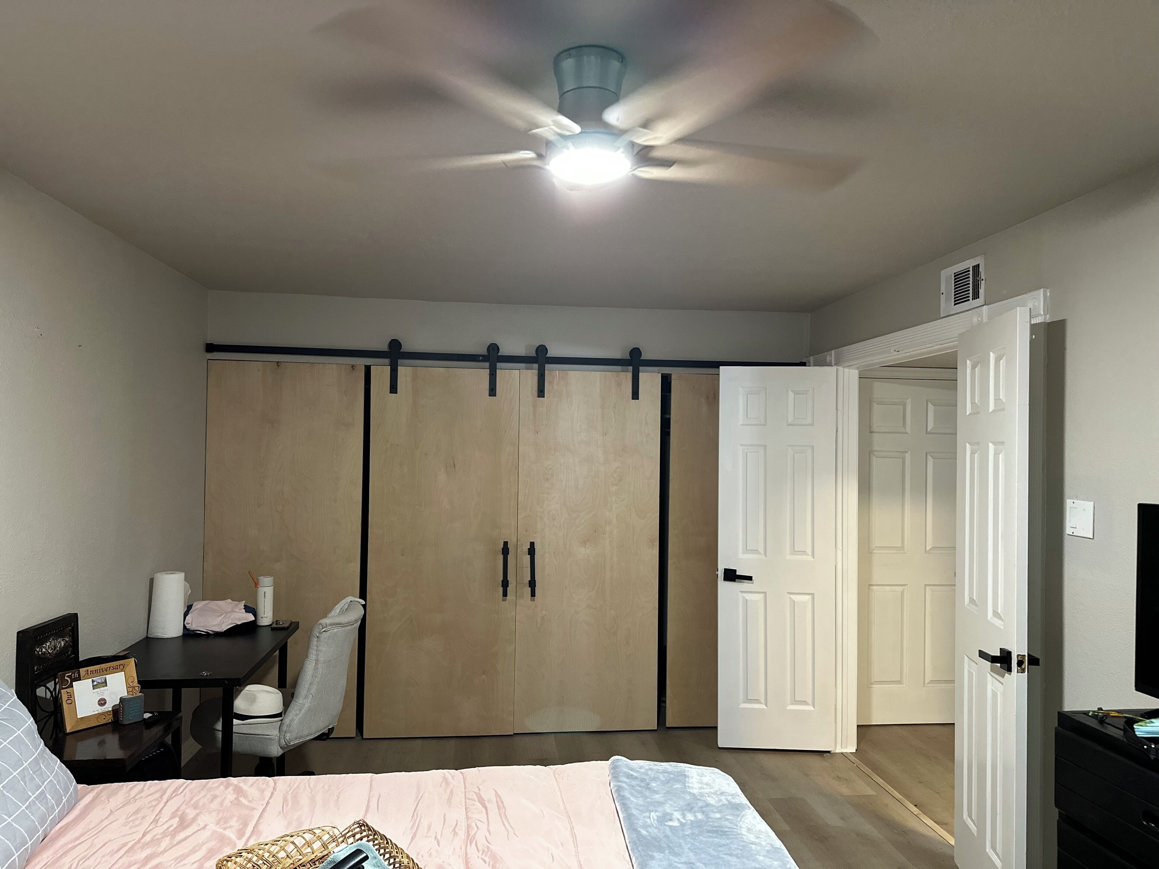 Une chambre à coucher avec un lit, un bureau, une chaise, une armoire et une porte.