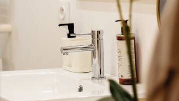Un lavabo de salle de bain doté d’un robinet moderne, d’un distributeur de savon et d’un miroir au-dessus.