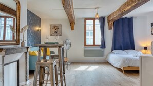 A compact room with a bed, a dining table, and a kitchenette.