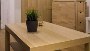 Una habitación con una mesa de madera, una planta en maceta y un armario de madera.