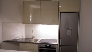 Una cocina con un refrigerador de acero inoxidable, un horno empotrado, un lavamanos y una estufa.