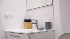 Un baño con inodoro, lavamanos, espejo y armario.