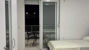 A bedroom with two beds, a sliding glass door leading to an outdoor area with chairs, and an air conditioning unit on the wall. - A family owned house (Ulcinj)
